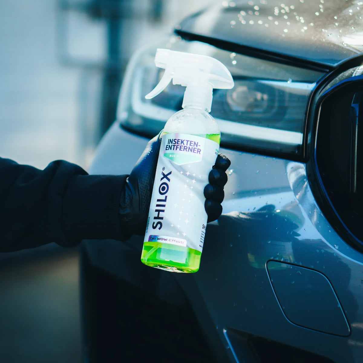 SHILOX Bogároldó 500 ml-es flakonban, kézben tartva az autó elejénél.